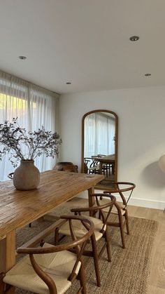 a wooden table with chairs and a vase on it