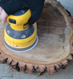 a person using a sander on top of a tree stump to cut down a large piece of wood