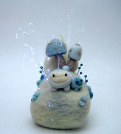 a small stuffed animal sitting on top of a white rock covered in blue and white bubbles