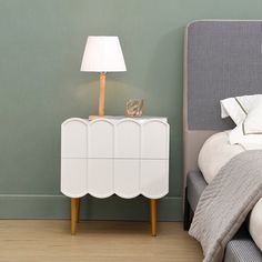 a white dresser next to a bed in a room with green walls and wooden floors