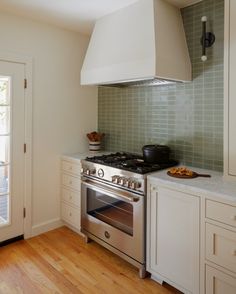 a stove top oven sitting inside of a kitchen next to a wooden floor and white cabinets