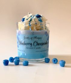 blueberry cheesecake in a glass jar surrounded by candy candies on a white surface