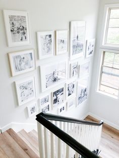 there are many pictures on the wall above the bannister and stair railings