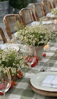 the table is set with plates, glasses and vases filled with flowers on it