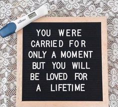 there is a black and white sign on the table next to a blue marker that says, you were carried for only a moment but you will be loved for a life time