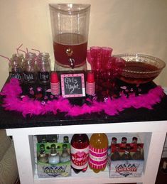 a table with drinks and pink feathers on it in front of a sign that says girls night