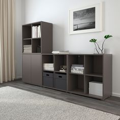 a living room with a book shelf and storage bins