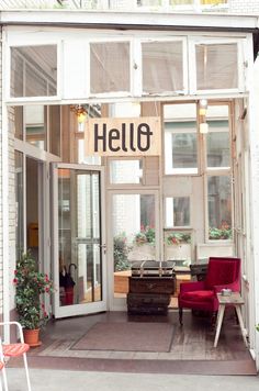 the entrance to a building with chairs and tables in front of it that says hello