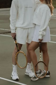 a man and woman standing on a tennis court holding racquets in their hands