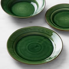 three green plates sitting on top of a white counter