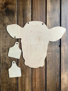 a wooden cow head with two tags attached to it's side on a wood background