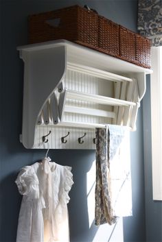 a shelf with clothes hanging on it next to a window in a blue walled room