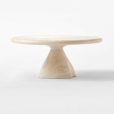 a white cake plate sitting on top of a tableclothed flooring area with an oval shaped base