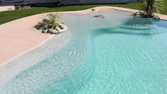 an aerial view of a swimming pool in the middle of a lawn and palm trees