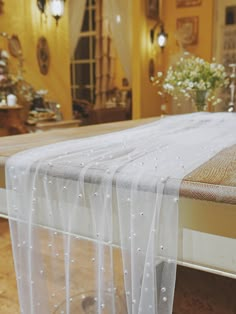 the bed is made up with white sheets and beaded trimmings on it