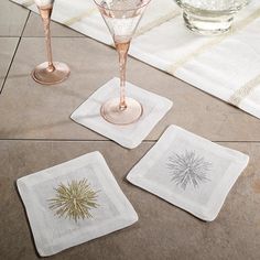 three wine glasses and two napkins sitting on a tile floor next to each other