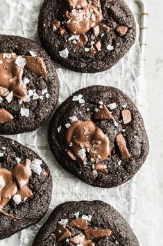 four chocolate cookies with sea salt on top and one cookie covered in brownie frosting