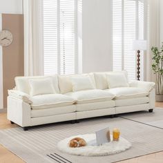 a living room with a white couch, rug and coffee table in front of windows