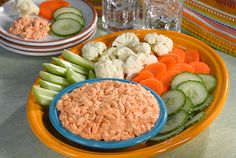 a plate with carrots, celery, cauliflower and cucumbers on it