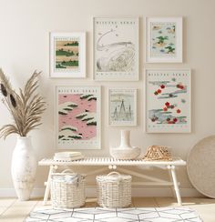 a white table topped with lots of pictures and vases next to a wall covered in art