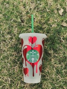 a starbucks cup sitting on top of grass covered in red and white paint with a green straw