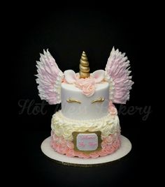 a cake decorated with pink and white icing, gold trimmings and an unicorn's horn on top