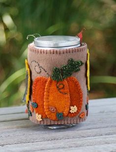 a can holder is decorated with an orange pumpkin