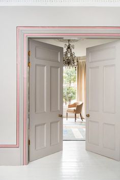 an open door leading to a living room with a chandelier hanging from the ceiling