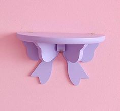 a purple shelf with two wings on it against a pink wall in the shape of an angel