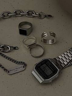 a bunch of different items that are laying on the ground together, including a watch and chain