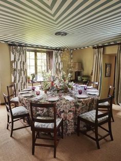 a dining room table set with place settings and flowers in vases on the table