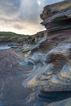 some rocks and water under a cloudy sky