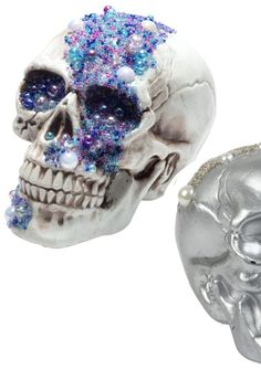 two silver skulls with blue and pink crystals on their heads, one skull is facing the other