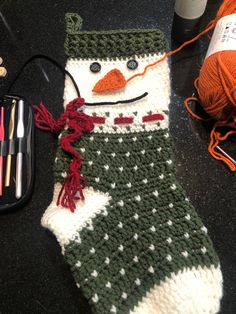 a knitted snowman stocking next to some yarn