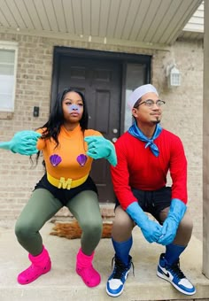 two people in costumes sitting on the front steps of a house with their hands painted