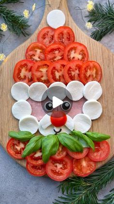 a wooden cutting board topped with sliced tomatoes and cheese cut into the shape of a face