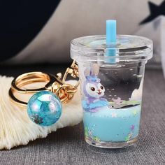 a cup with a keychain on it sitting next to a brush and ball