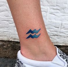 a small tattoo on the ankle of a woman's foot, with waves in blue ink