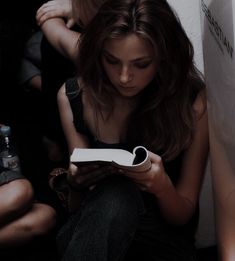 a woman sitting on the floor looking at her cell phone while another person sits next to her