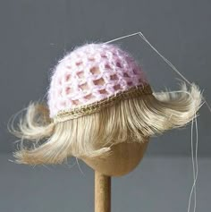 a doll head with blonde hair and a pink knitted hat on it's head