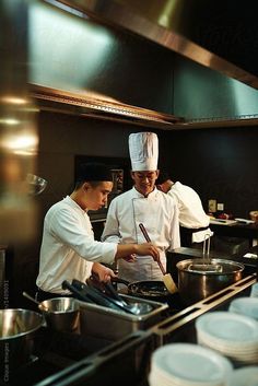 two chefs preparing food in a kitchen with plates and utensils on the counter