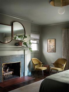 a bedroom with a fireplace, mirror and chair next to the bed in front of it