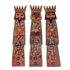 two wooden dolls with crowns on their heads, one is wearing a flowered dress