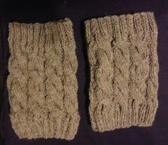 two knitted mittens sitting next to each other on a black tablecloth covered surface