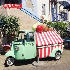 an ice cream truck parked in front of a building with a striped awning on top