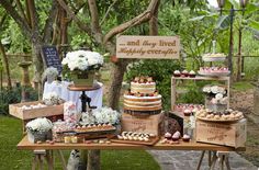 a table topped with cakes and cupcakes on top of a wooden table covered in flowers