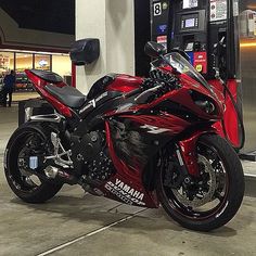 a red motorcycle parked in front of a gas pump