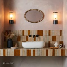 a bathroom sink sitting under a mirror next to two wall sconces and lights