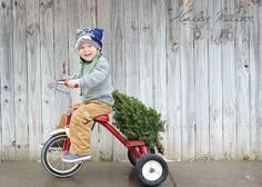 a young boy riding a red bike with a christmas tree on the handlebars