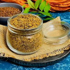 three jars filled with different types of spices on top of a blue table cloth next to bowls